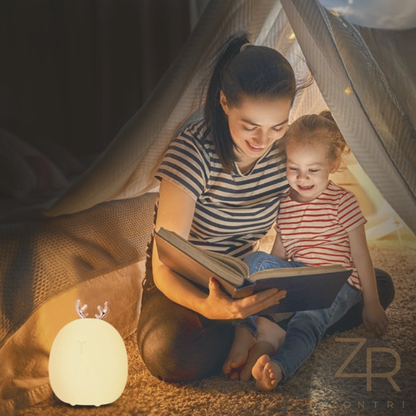 Mom and daughter reading a book inside a tent with a glowing silicone deer night light on the floor.