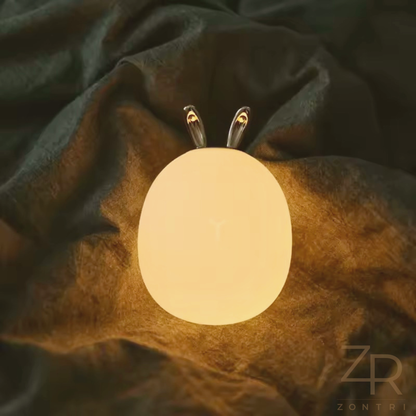 Styled nursery shelf or sideboard decorated with books, toys and a glowing silicone rabbit or deer night light.